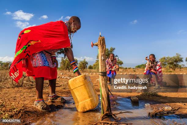 afrikanische frau aus maasai-stamm sammelt wasser, kenia, ostafrika - african village stock-fotos und bilder