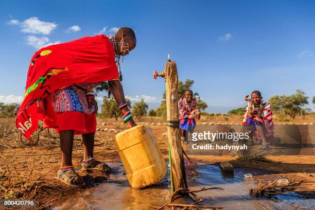 mujer africana de la tribu masai recogiendo agua, kenia, áfrica oriental - carrying fotografías e imágenes de stock