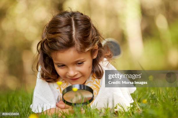 girl looking at grass through magnifying glass - interest stock pictures, royalty-free photos & images