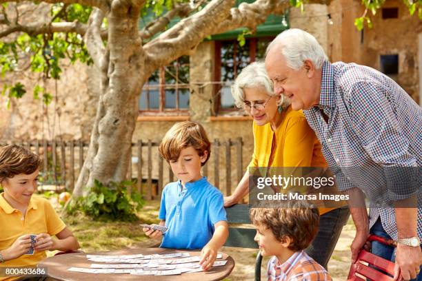 grands-parents, regardant les enfants jeux de cartes - grand parent photos et images de collection