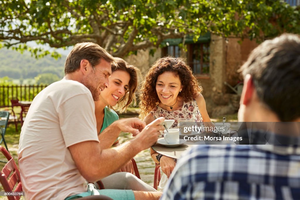 Man showing mobile phone to female friends in yard