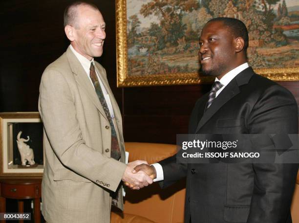 Ivory's Coasts Prime Minister Guillaume Soro shakes hands with International Monetary Fund Representative Arend Kouwenaar in Abidjan on February 28,...