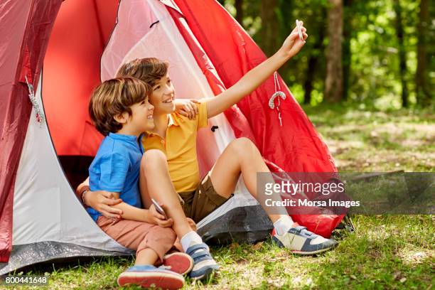 hermanos felizes toman selfie por carpa en el bosque - boyshorts fotografías e imágenes de stock