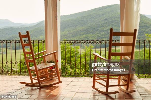 empty rocking chairs in balcony against mountains - rocking chair stock pictures, royalty-free photos & images