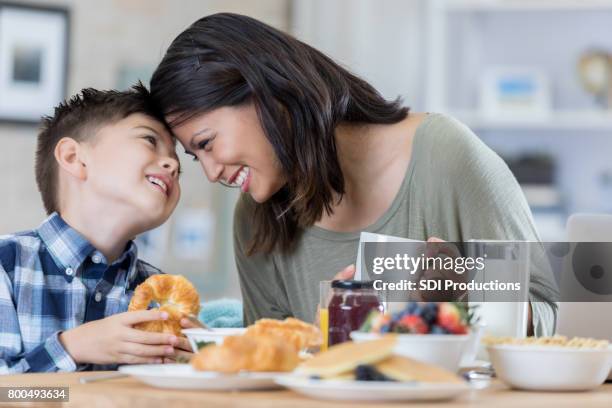 playful mom enjoys breakfast at home with her son - filipino family eating stock pictures, royalty-free photos & images