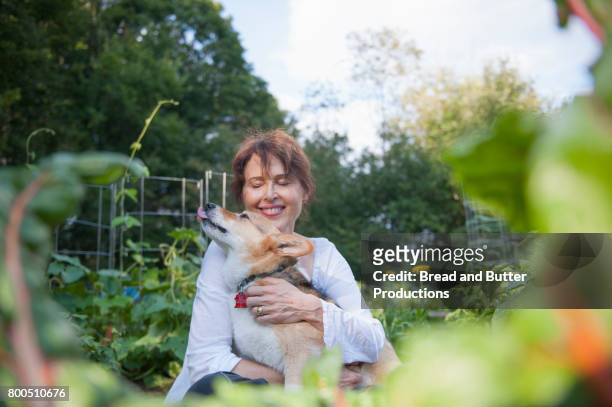 Smiling Adult Woman Hugging Corgi Dog Outdoors in the Garden