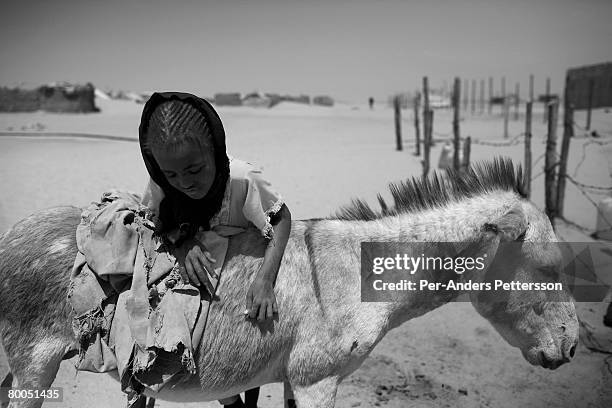 Refugee girl climbs a donkey after fetching water at the Oure Cassoni refugee camp on July 26, 2007 about 23 kilometers outside Bahai, Chad. Since...
