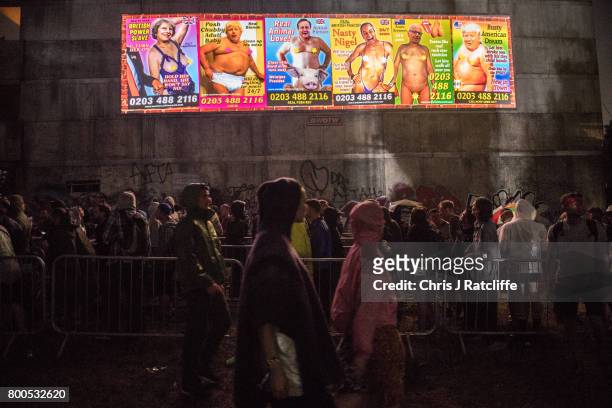 Revellers queue underneath a politcal sign mocking world politicians to enter a club in Block 9 in the Shangri La area at Glastonbury Festival Site...