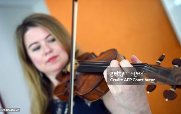 Violinist Lara St. John poses with her instrument, an anonymously donated Salabue Guadagnini from 1779, during an interview with AFP at her apartment...