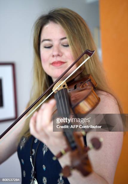 Violinist Lara St. John poses with her instrument, an anonymously donated Salabue Guadagnini from 1779, during an interview with AFP at her apartment...