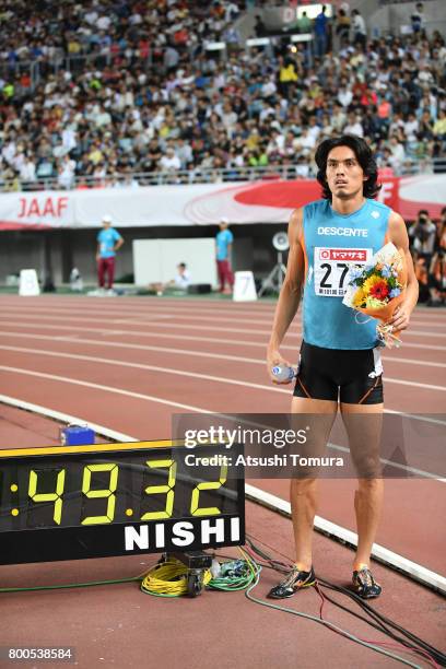 Takatoshi Abe of Japan poses with the time clock after winning in the Men's 400m hurdles final during the 101st Japan National Championships at...