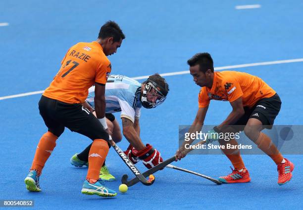 Razie Rahim of Malaysia and Faizal Saari of Malaysia battle for possession with Manuel Brunet of Argentina during the semi-final match between...