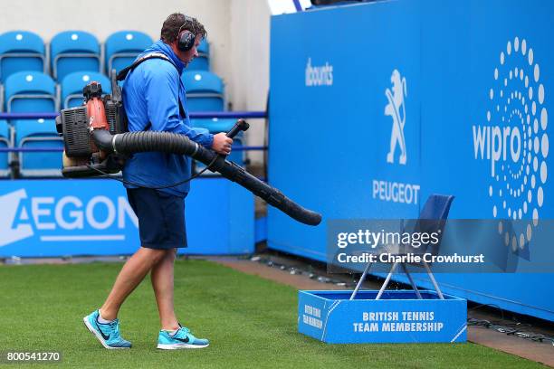 Grounds man tries to dry out a line judges chair on court one after a long rain delay during Qualifying on Day 2 of The Aegon International...