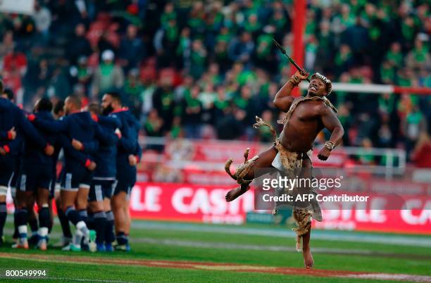 French players form a huddle as a Zulu warrior performs during the opening ceremony ahead of the third rugby union Test match between South Africa...
