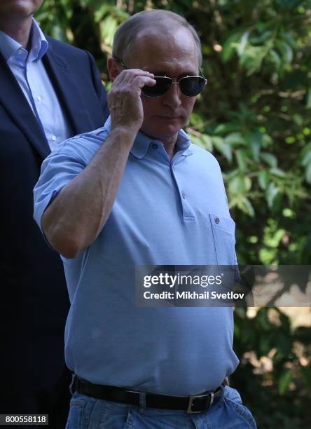 Russian President Vladimir Putin touches his sunglasses while visiting Artek camp, an international children center on the Black Sea on June 24, 2017...