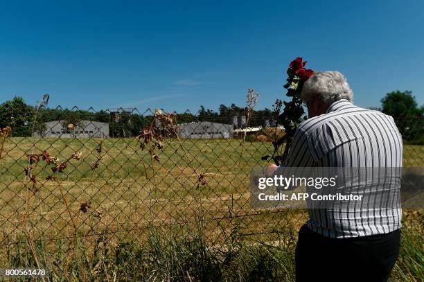 Roma man lays a flower on the fence of the industrial pig farm situated at the site of a former concentration camp in Lety, Czech Republic, on June...