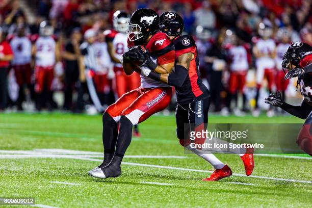 Calgary Stampeders wide receiver Lemar Durant attempts to break a tackle by Ottawa RedBlacks defensive back A.J. Jefferson during Canadian Football...