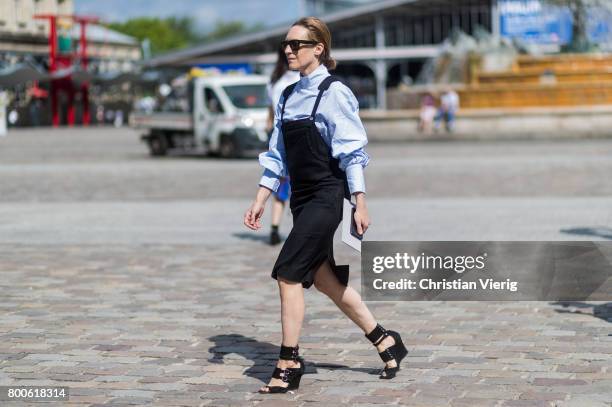 Guest wearing a black overall dress, button shirt, heeled sandals outside Sacai during Paris Fashion Week Menswear Spring/Summer 2018 Day Four on...