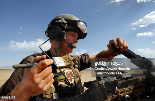 Prince Harry cleans the dust from the machine gun on his Spartan armoured vehicle in the desert on February 20, 2008 in Helmand Province, Afghanistan.