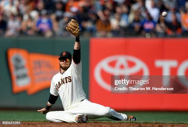 Brandon Crawford of the San Francisco Giants falls to the ground and watches the ball kick over the top of his glove for a single off the bat of...