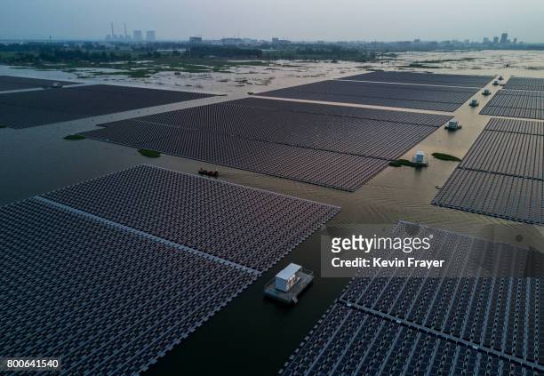 Chinese workers ride in a boat through a large floating solar farm project under construction by the Sungrow Power Supply Company on a lake caused by...