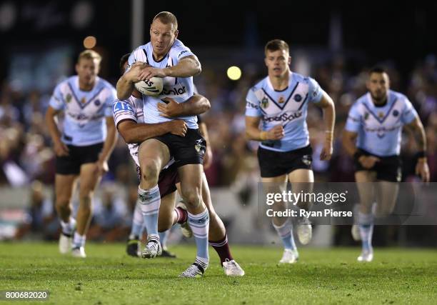 Luke Lewis of the Sharks is tackled during the round 16 NRL match between the Cronulla Sharks and the Manly Sea Eagles at Southern Cross Group...