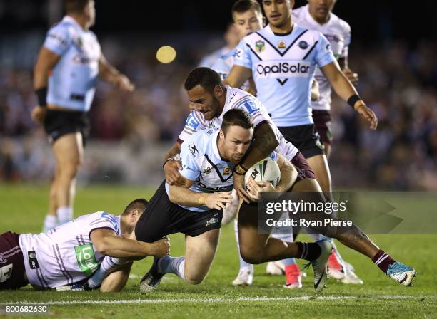 James Maloney of the Sharks is tackled by Api Koroisau of the Sea Eagles during the round 16 NRL match between the Cronulla Sharks and the Manly Sea...