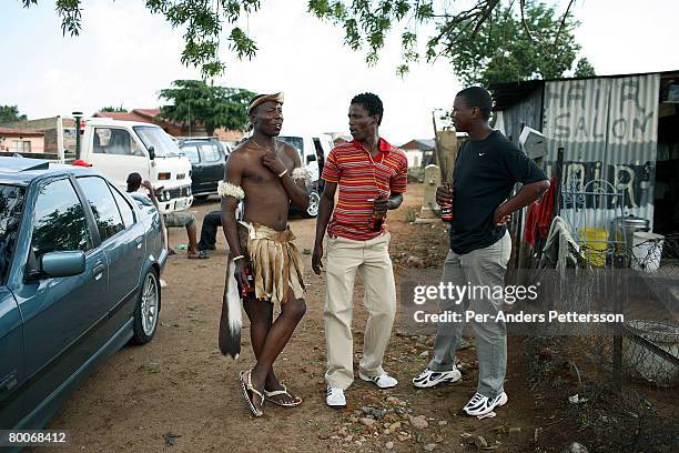 Traditional Zulu dance group member drinks a beer with a few friends before a performance at a wedding reception October 28, 2006 in Diepkloof...