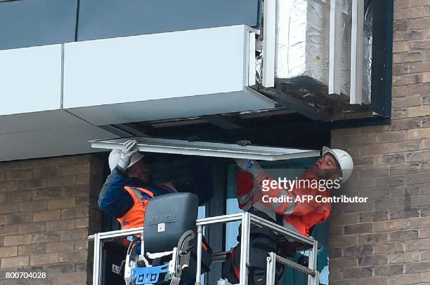 Workers remove panels of external cladding from the facade of a building in the Wythenshawe area of Manchester, northwest England, on June 25, 2017....