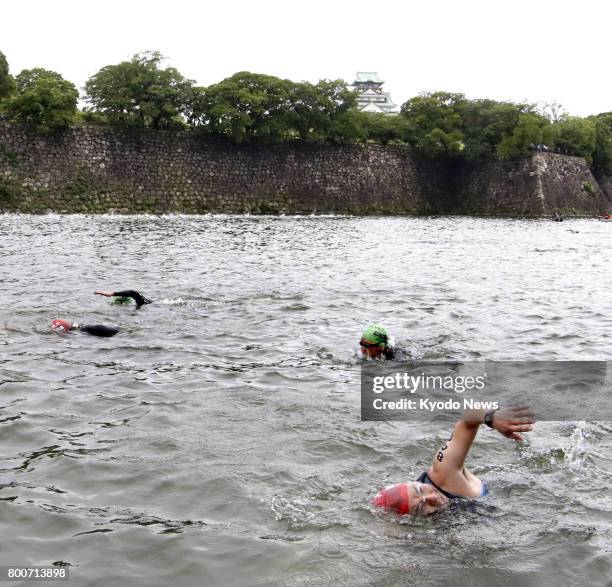 Triathletes swim in a water-filled moat beside Osaka Castle on June 25, 2017. About 900 people took part in the first triathlon competition using a...