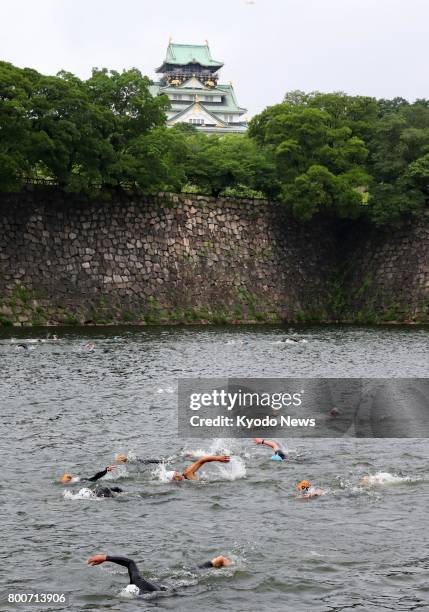 Triathletes swim in a water-filled moat beside Osaka Castle on June 25, 2017. About 900 people took part in the first triathlon competition using a...