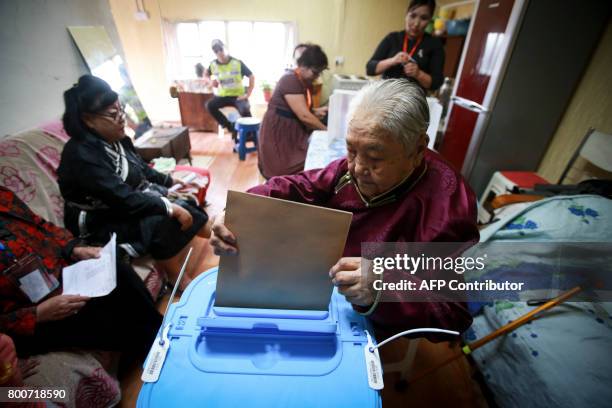 An elderly woman votes with portable voting box as she can't move from her home, on the eve of Mongolian presidential election in Ulan Bator, on June...