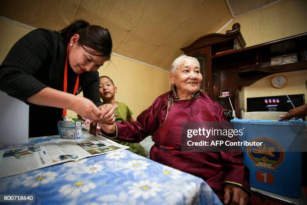 An official marks with ink the finger of an elderly woman after she votes with portable voting box as she can't move from her home, on the eve of...