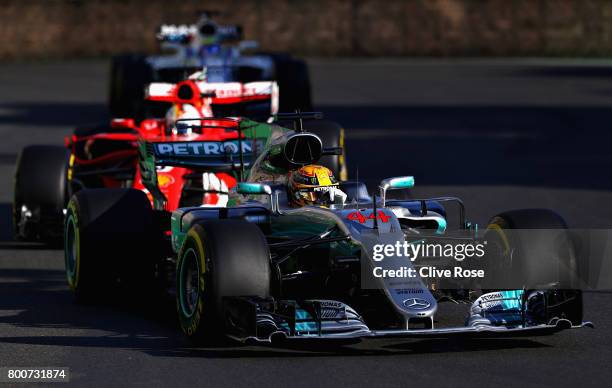 Lewis Hamilton of Great Britain driving the Mercedes AMG Petronas F1 Team Mercedes F1 WO8 leads Sebastian Vettel of Germany driving the Scuderia...