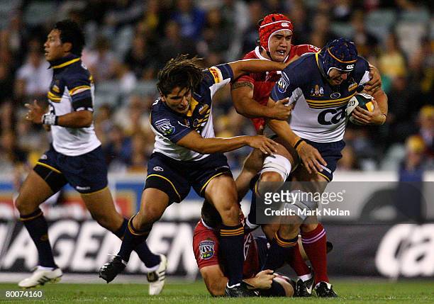Saia Faingaa and Mark Chisholm of the Brumbies collide as Leroy Houston of the Reds tackles during the round three Super 14 match between the ACT...