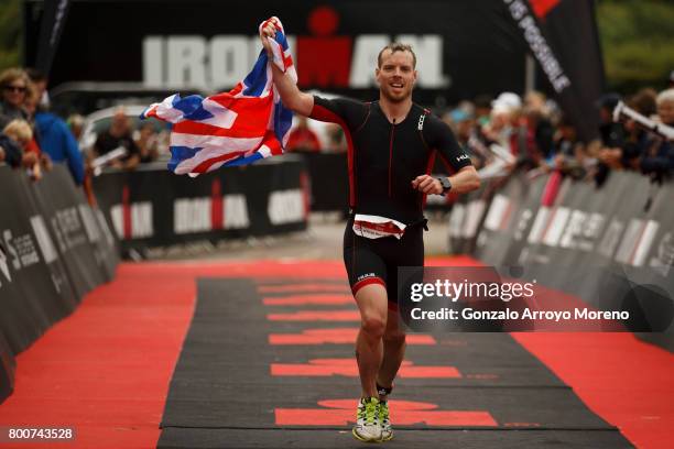 An athlete holds the Union Jack flag as he crosses the finish line during the Ironman 70.3 UK Exmoor at Wimbleball Lake on June 25, 2017 in Somerset,...