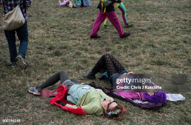 Two women wearing a wig and a flower garland sleep during the afternoon at the Pyramid Stage at Glastonbury Festival Site on June 25, 2017 in...