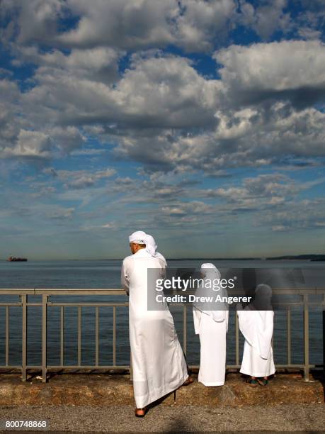 Muslim family looks out toward Gravesend Bay before a group prayer service during Eid al-Fitr, which marks the end of the Muslim holy month of...