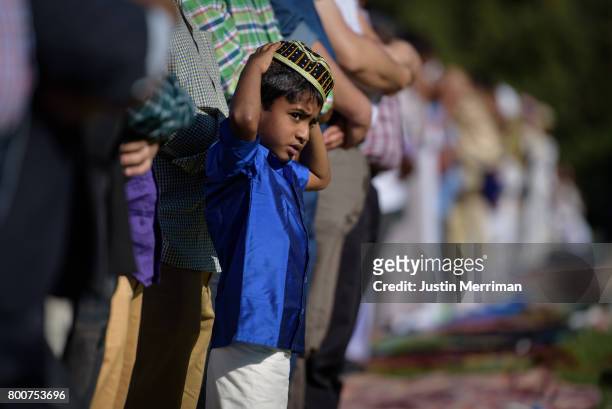Young Muslim boy stands with the men as they pray during a celebration of Eid al-Fitr, a holiday marking the end of Ramadan, on June 25, 2017 in...