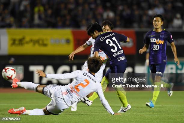 Takumi Miyayoshi of Sanfrecce Hiroshima shoots at goal while Kosuke Kikuchi of Omiya Ardija tries to block during the J.League J1 match between...