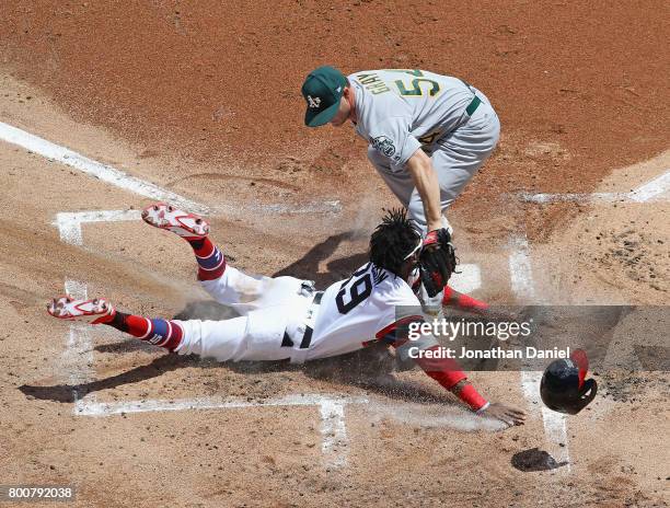 Alen Hanson of the Chicago White Sox is tagged out at the plate after a wild pitch by starting pitcher Sonny Gray of the Oakland Athletics in the 1st...