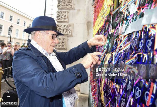 Ian McKellen ties a lock with a personal message onto the rainbow coloured love locks display on West gates at the Old Royal Naval College on June...