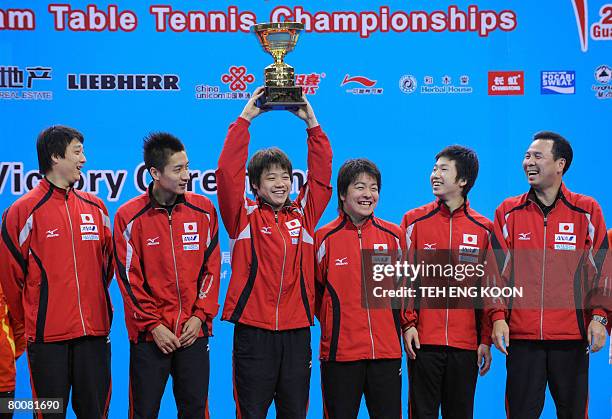 Japan's team members share a joke with their third runner up trophy on the podium of the World Team Table Tennis Championships in Guangzhou, China's...