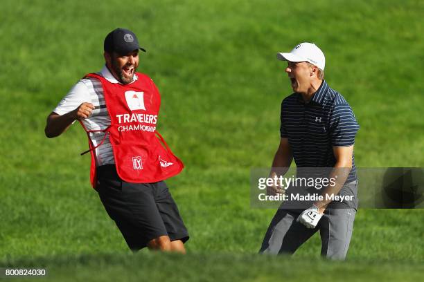 Jordan Spieth of the United States celebrates with caddie Michael Greller after chipping in for birdie from a bunker on the 18th green to win the...