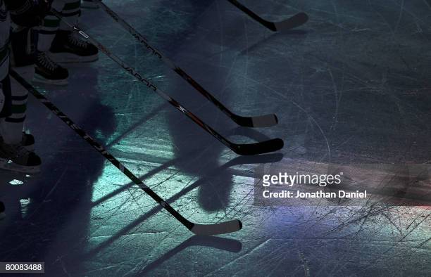 Players rest their sticks on the ice during the playing of the national anthem prior to the NHL game between the Chicago Blackhawks and the Vancouver...