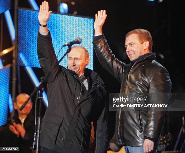 Russian President Vladimir Putin and his likely successor Dmitry Medvedev wave as they make a surprise appearance at a rock concert near Red Square...