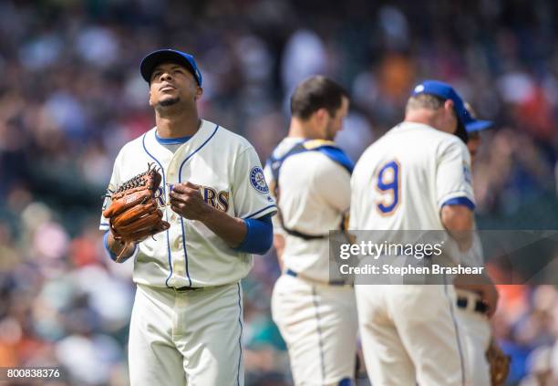 Starting pitcher Ariel Miranda of the Seattle Mariners pounds his glove as he walks off the field after getting pulled in the eighth inning of a game...