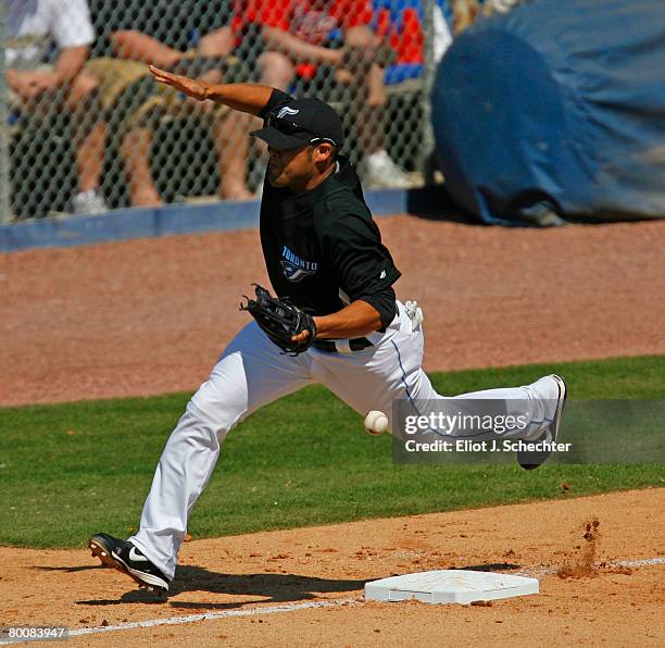 Sergio Santos of the Toronto Blue Jays has trouble fielding a ball as a run scores against the Cincinnati Reds during a Spring Training game at...