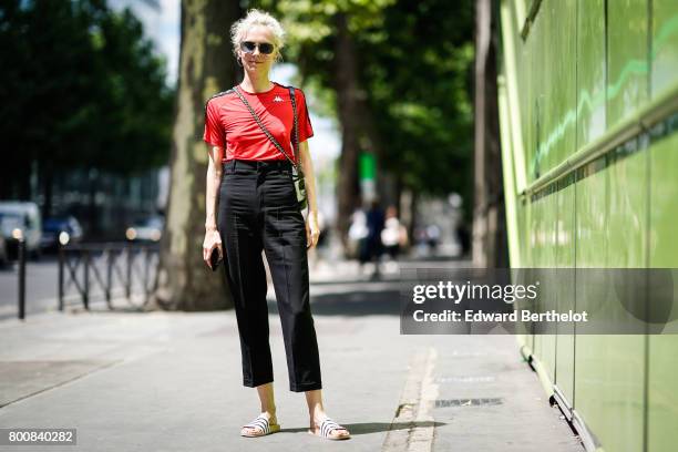 Olga Karput wears sunglasses, a red top, black pants, sandals, outside the Y-3 show, during Paris Fashion Week - Menswear Spring/Summer 2018, on June...