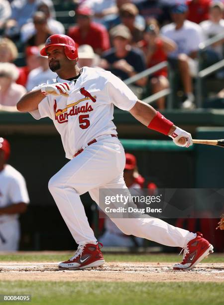 Albert Pujols of the St. Louis Cardinals follows through on a single against the Florida Marlins during a Spring Training game at Roger Dean Stadium...